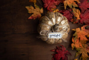 Pumpkin on table that has written note saying, "Grateful."